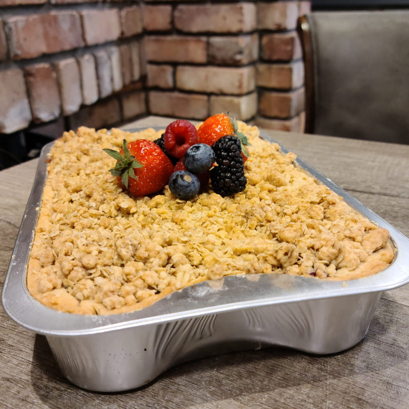 Apple and winterberry crumble on a wooden table with a brick wall background