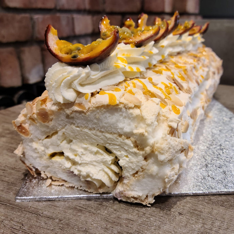 Roulade with whipped cream and passion fruit on a wooden surface