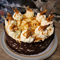 Salted Caramel Cheesecake decorated with cream, chocolate swirls and caramel