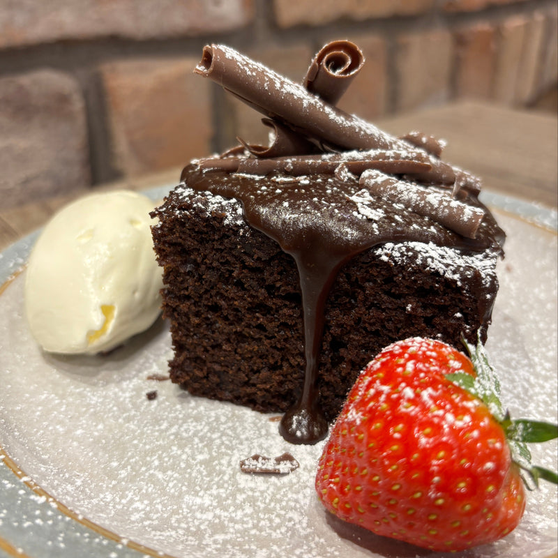Chocolate cake with a strawberry and cream on a Denby plate.