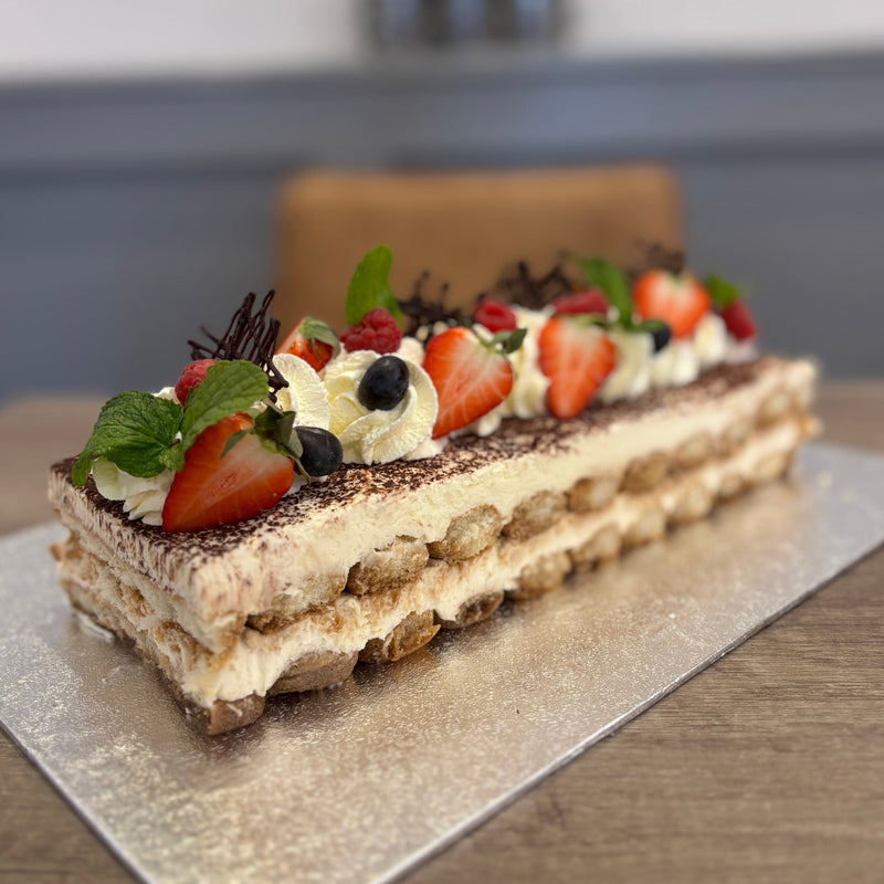 Layered tiramisu with strawberries and cream on a silver tray